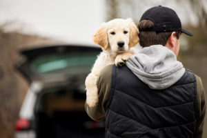 man outdoors turned around holding a puppy