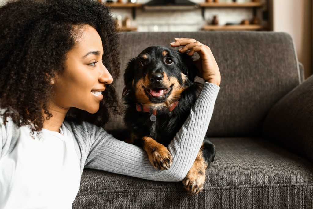 Woman sitting in front of couch with her arm around dog