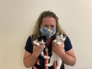 foster volunteer wearing mask holding two kittens