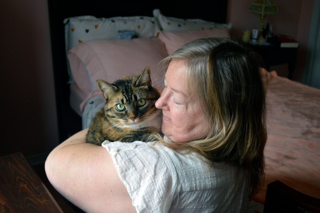 foster volunteer holding a cat in a home