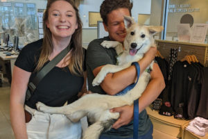 adoption celebration photo, man holding dog in his arms and lady smiling next to them
