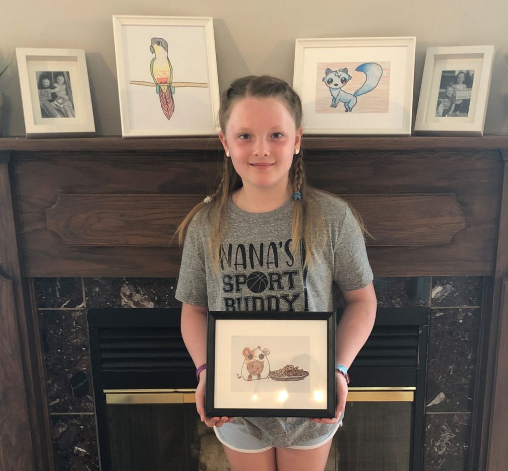 Young girl holding a framed photo of art she made